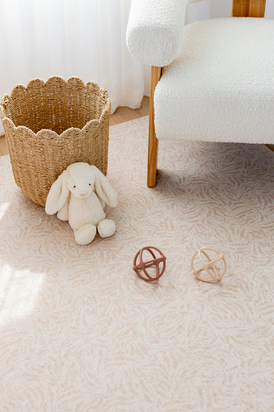 River Bend-pattern play mat beneath a white armchair, with a soft rabbit, woven basket and toy balls