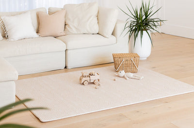 Large Arch-pattern play mat in front of a cream sofa, with a toy truck, soft rabbit and wicker basket