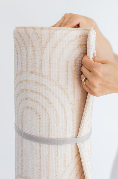 Close-up of a hand bending the edge of a rolled Arch-pattern play mat