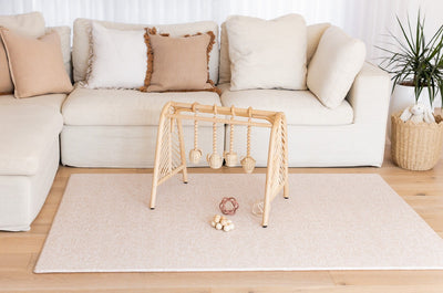 River Bend-pattern play mat with a wooden play gym centred in front of a cream sofa